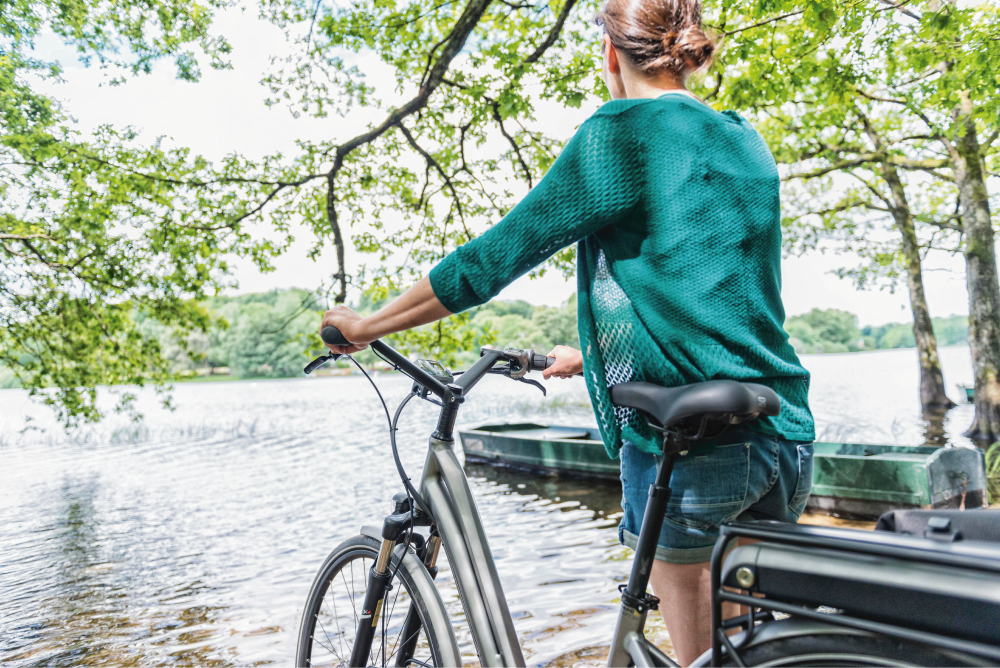 Femme avec un VTC à assistance électrique au bord d'un lac