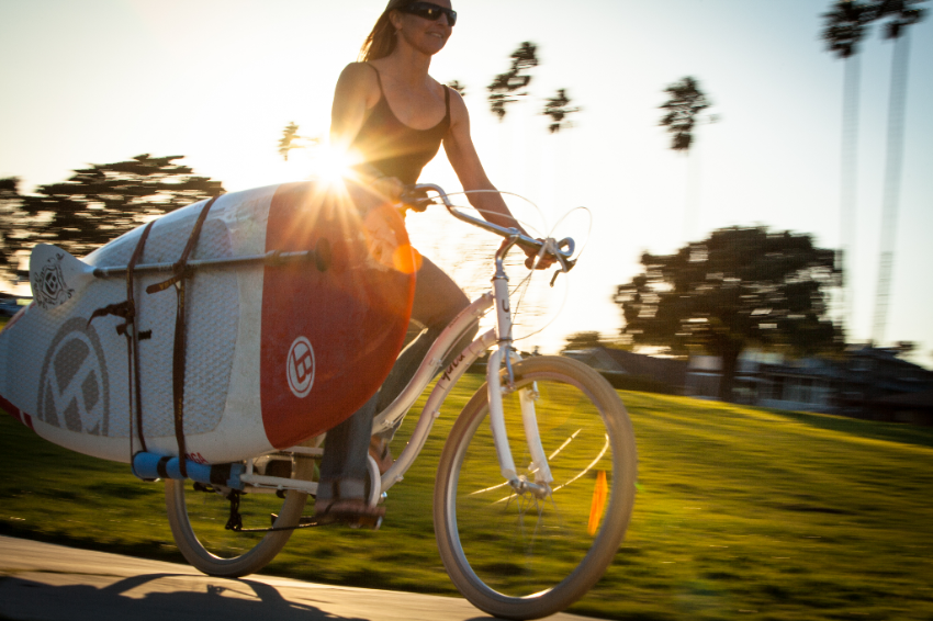 Femme sur un vélo Yuba transportant un surf