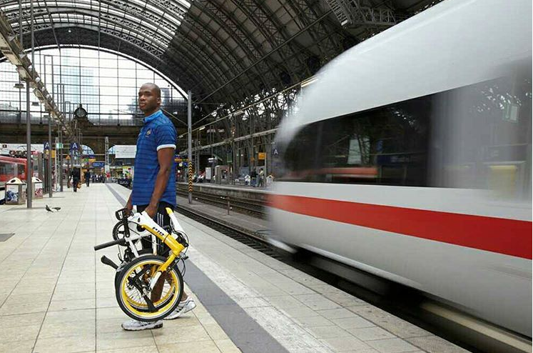 Cycliste sur le quai d'une gare avec son vélo pliant plié à la main