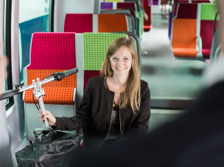 Jeune femme voyageant avec son vélo pliable dans un train SNCF