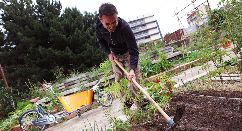 Jardinier avec vélo cargo utilitaire en fond
