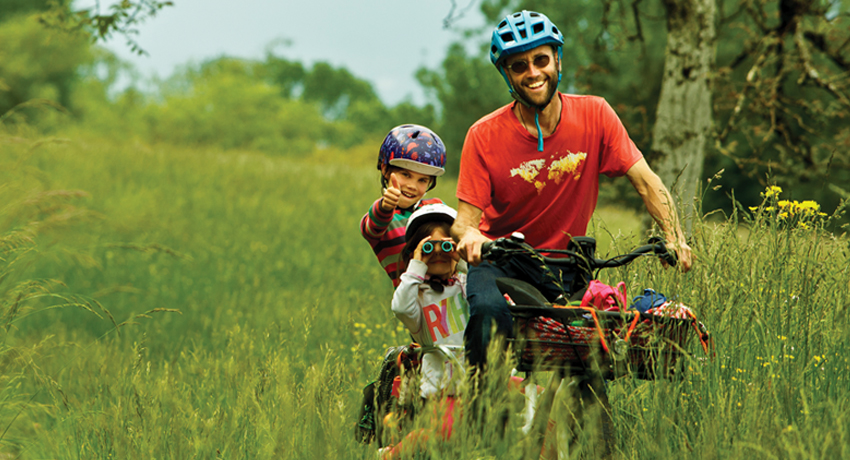 Damien et ses filles dans les prés sur leur vélo cargo