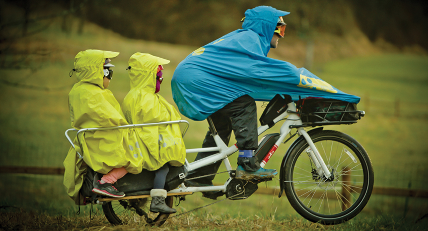 Damien et ses filles sur leur vélo cargo équipés de ponchos