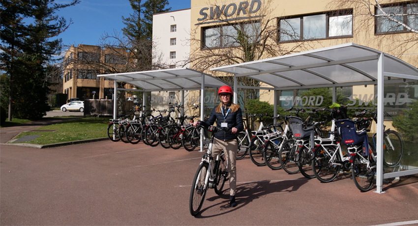Femme utilisant un vélo de fonction devant le siège de son entreprise