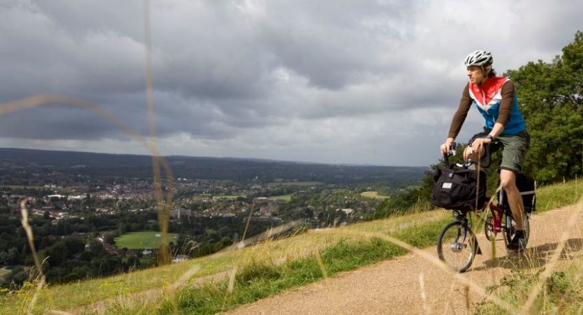 Un randonneur sur un vélo pliant roule sur un chemin à flanc de colline.
