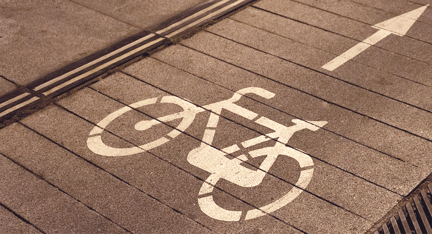Un logo vélo blanc apposé sur une piste cyclable.