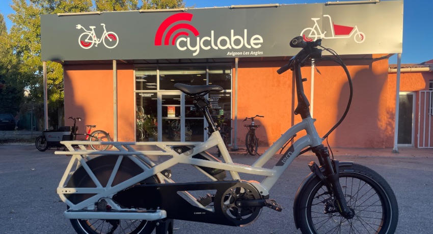 Au premier plan, un vélo longtail Tern. Derrière, vue sur la devanture rénovée de Cyclable Avignon-Les Angles.