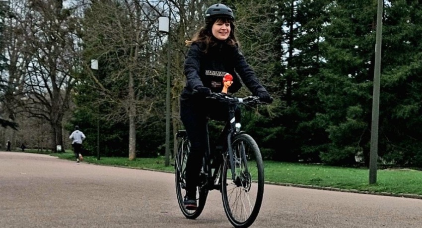 Charline, collaboratrice Cyclable au sein du pôle communication, à vélo dans un parc.
