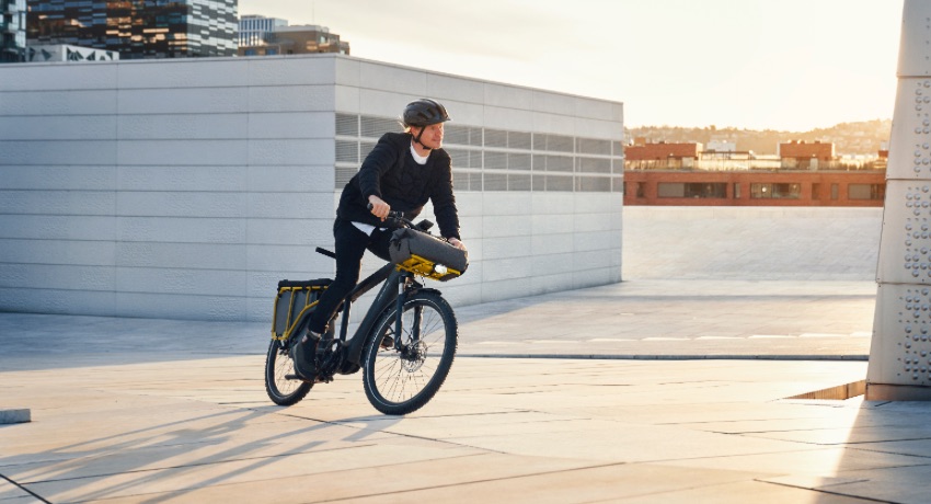 Un homme pédale en ville sur un Riese&Müller Multicharger, un longtail dont l'apparence s'approche de celle d'un vélo classique