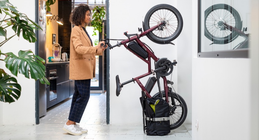 Une femme range son longtail Tern Quick Haul à la verticale une fois arrivée au bureau.