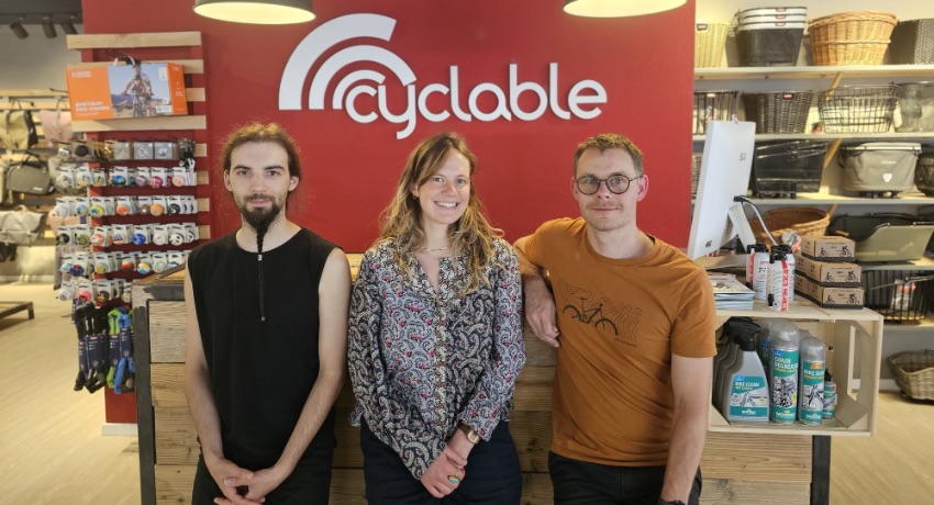 L'équipe de Cyclable Bienne devant le comptoir rouge du magasin.
