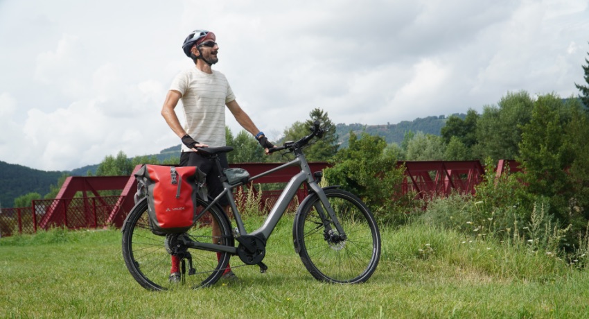 Un cycliste tient son VAE Kalkhoff Endeavour L près d'un ancien pont ferroviaire sur la Via Fluvia.