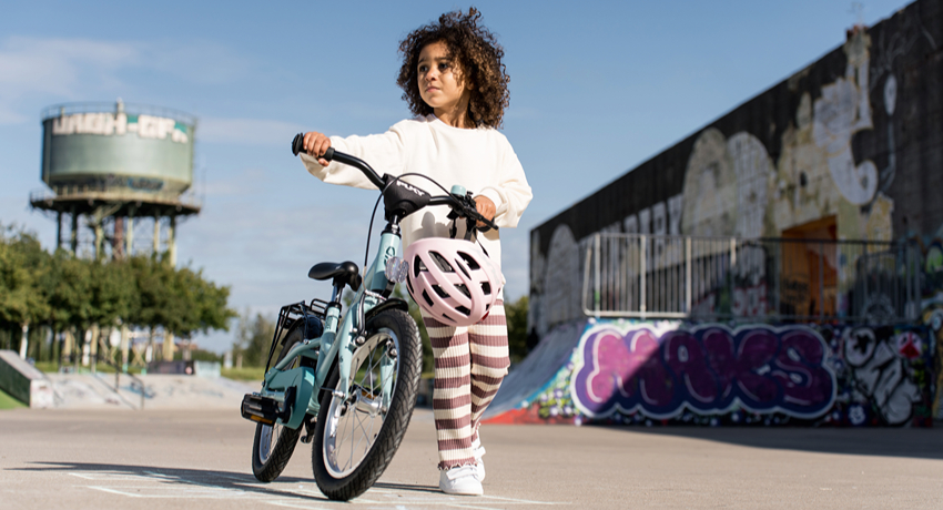 Une petite fille pousse un vélo Puky dans un skatepark.